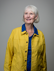 waist-up photo of Diana Hunter, caucasian female with short white hair, wearing a yellow collared jacket lined with blue